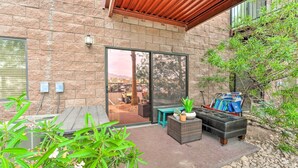 Un espace patio agrémenté d’un mur en pierre, d’une porte-fenêtre coulissante, de mobilier d’extérieur et de plantes en pot.