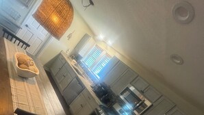 A modern kitchen with stainless steel appliances, a dining area with a wooden table and chairs, and a hanging light fixture. - Water Front Home: Fisherman's' dream with private dock and beautiful sunsets (Brownstown Charter Township)