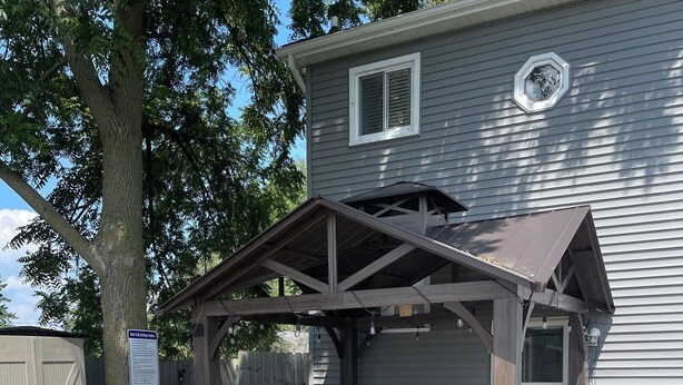 A covered outdoor patio with a grill, seating, and a hot tub. - Water Front Home: Fisherman's' dream with private dock and beautiful sunsets (Brownstown Charter Township)