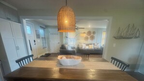 A dining area with a wooden table, chairs, a woven pendant light, and a bowl on the table. - Water Front Home: Fisherman's' dream with private dock and beautiful sunsets (Brownstown Charter Township)