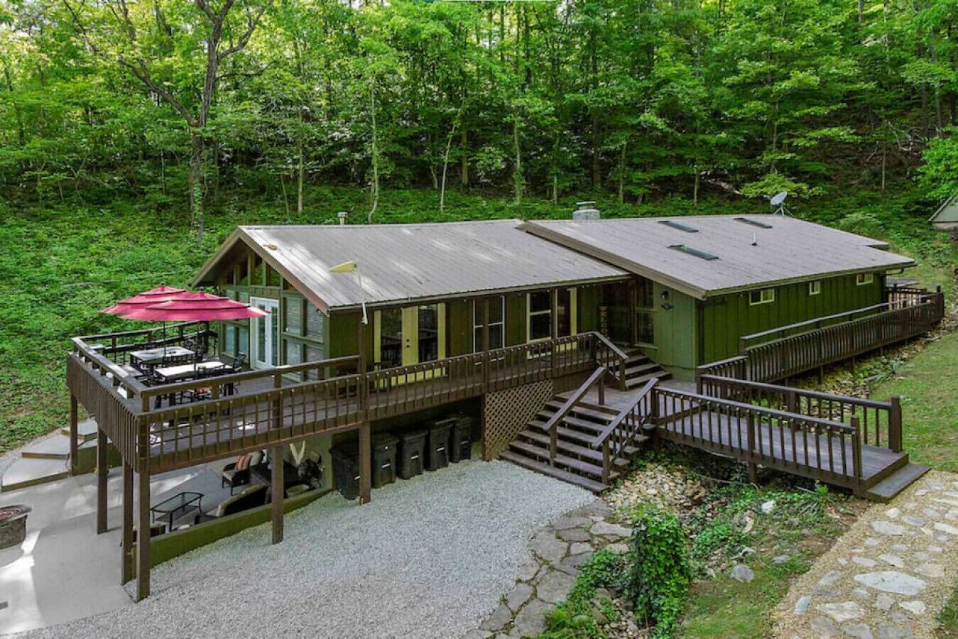 A cabin with a deck, outdoor seating, and a staircase leading to a second level.