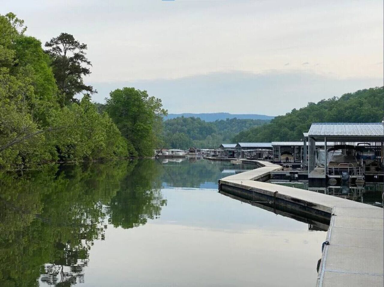 A calm lake with docked boats and a small building with a metal roof.