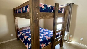 A bunk bed with floral bedding in a room with tiled flooring and a sloped ceiling. - Hunter's Ridge Cabins - 1 (Concan)