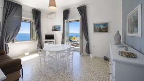 A room with a dining table, chairs, a TV, and a view of the sea. - Mareblù in Praiano centre (Praiano)