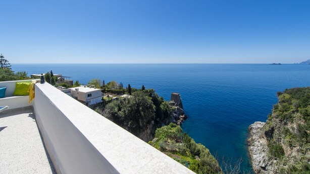 A coastal view from a balcony overlooking a clear blue sea, with buildings and greenery in the background. - Mareblù in Praiano centre (Praiano)