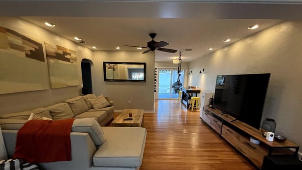 A modern living room with a sofa, a coffee table, a TV, and a ceiling fan.