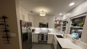 A modern kitchen with stainless steel appliances, white cabinetry, and a built-in oven.