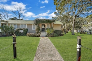 Stroll up the gravel pathway to the front door, surrounded by lush lawns and trees.