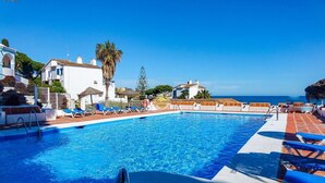Une piscine avec une eau d’un bleu cristallin, des chaises longues et une vue sur la mer.