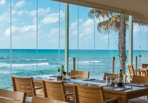 A dining area with a view of the ocean, wooden chairs, and a table set for two. - Mansion Apartment Frontal Sea Views (Mijas)