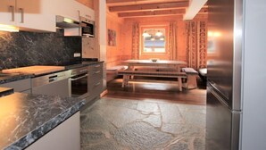 Een moderne keuken met granieten aanrechtbladen, een ingebouwde oven en een roestvrijstalen koelkast.