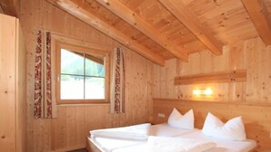 Een houten kamer met een bed, een raam en een wandlamp.