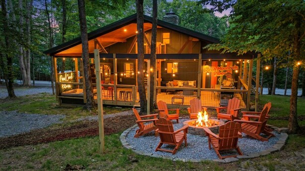 Un chalet doté d’une terrasse couverte, d’un foyer extérieur et de meubles de jardin.