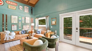 Une chambre confortable, aménagée dans le style d’un chalet, avec une grande fenêtre, un ensemble de canapés et divers tableaux encadrés accrochés aux murs.