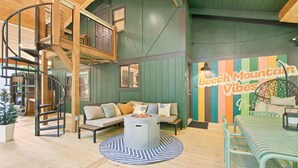 Un intérieur chaleureux avec un escalier en colimaçon, un ensemble de canapés, une table ronde et un mur coloré orné de l'inscription « Beech Mountain Vibes ».