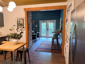 A kitchen with a wooden table, bar stools, a refrigerator, and a stone wall.