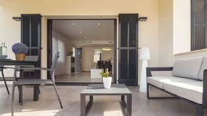 A modern living room with a sofa, a coffee table, and a dining area with chairs and a table.