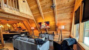 Ein gemütliches Wohnzimmer im Loft-Stil mit Holzboden, Kamin, einer Couch, einem Couchtisch und einem Fernseher.