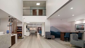 Un hall d’entrée spacieux comprenant un comptoir d’accueil, un espace salon et un escalier menant à un niveau supérieur.