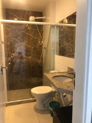 A bathroom with a glass-enclosed shower, a white toilet, a granite countertop, and a marble backsplash. - porto plaza flat (Ipojuca)