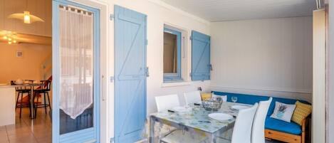 A dining area with a table set for four, a blue door, and a bench with cushions.
