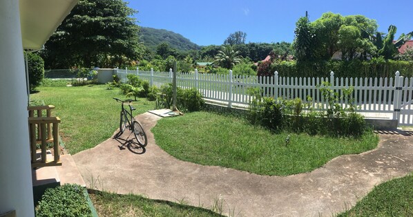 A well-maintained garden with a white picket fence, a bicycle, and a paved path.