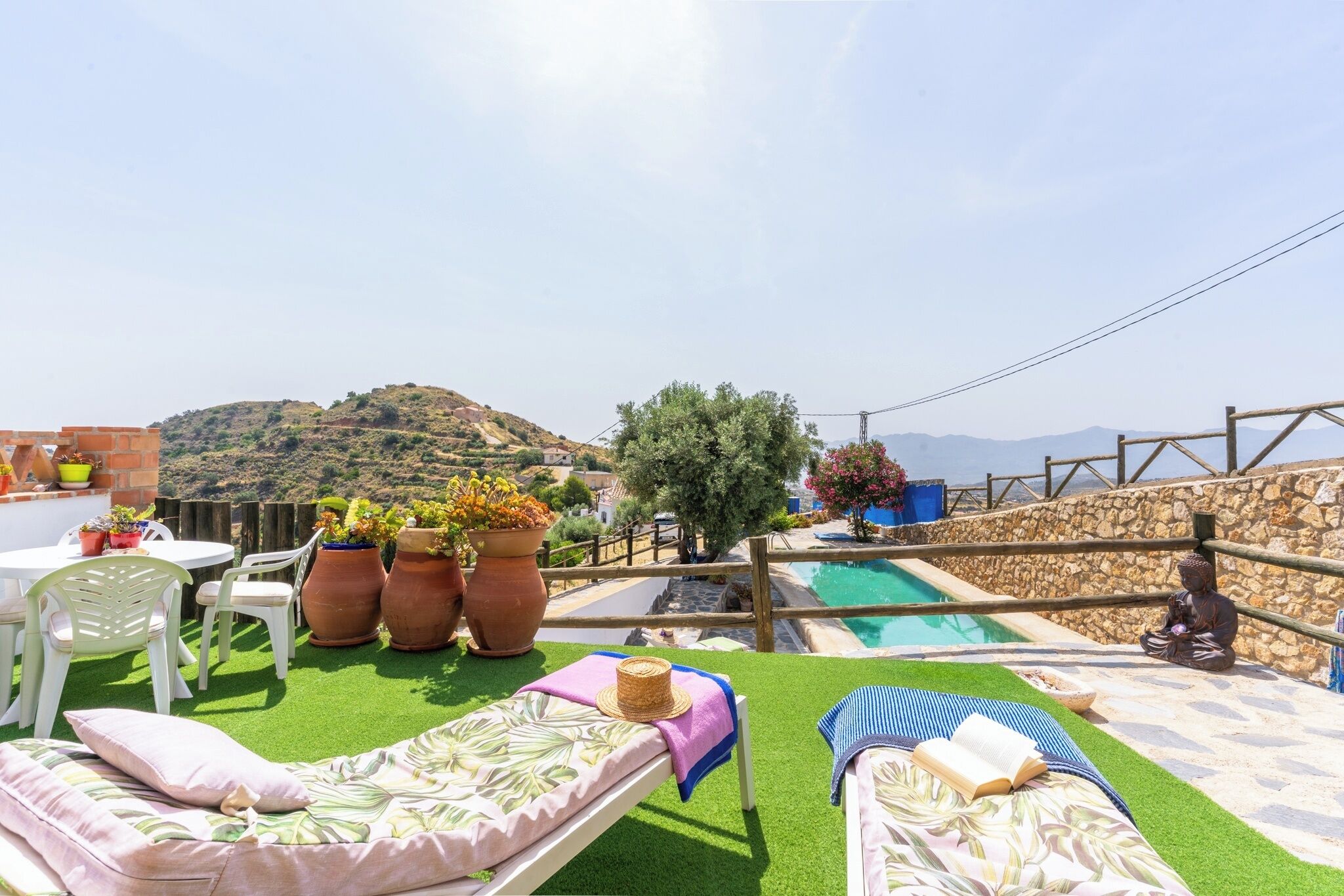 A rooftop terrace with a swimming pool, lounge chairs, and potted plants.
