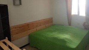A bedroom with a wooden headboard, a green bedspread, and a wall-mounted light fixture. - 3 Bed Flat - Sleeps 5 - Parking - Wifi (Tarifa)