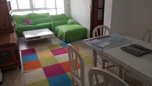 A room with a green sofa, a white table, and a colorful rug. - 3 Bed Flat - Sleeps 5 - Parking - Wifi (Tarifa)