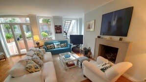 Ein Wohnzimmer mit einem blauen Sofa, weißen Sesseln, einem Couchtisch und einem Kamin.