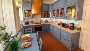Eine Küche mit blauen Schränken, einer Holzausziehtischplatte, einem Toaster, einem Wasserkocher und einer Kaffeemaschine.