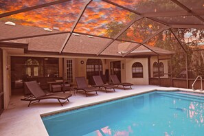 Ein Poolbereich mit Liegestühlen, einer überdachten Terrasse und Blick zum Himmel.