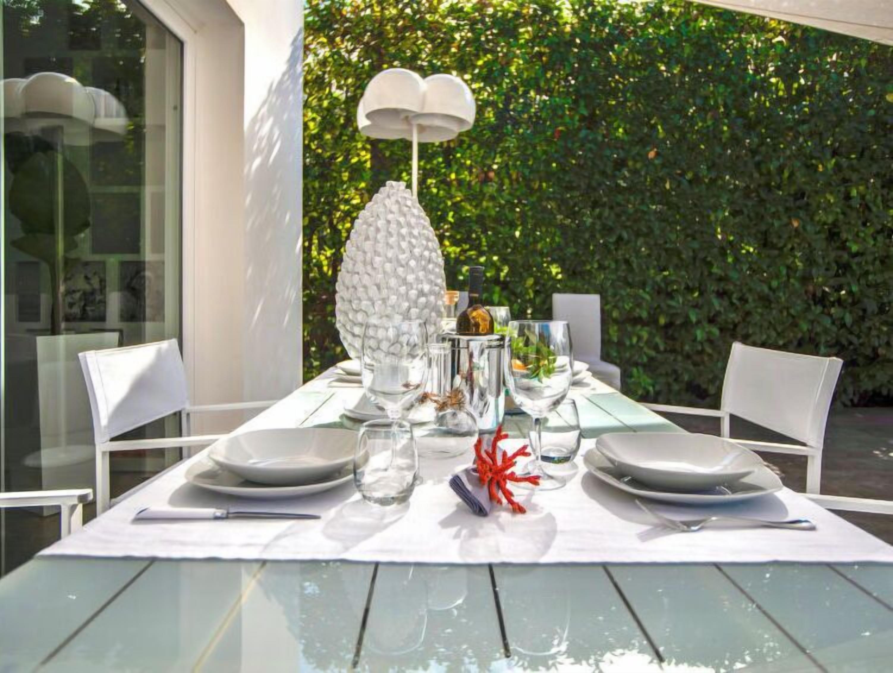 Une table dressée pour deux personnes, avec de l’assiette blanche, des verres transparents et un centre de table décoratif.