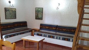 Une pièce chaleureuse avec un banc en bois, une petite table et un escalier.