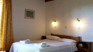 Une pièce avec un plafond en bois, un lit avec une literie blanche, deux lampes fixées au mur et un tableau accroché au mur.