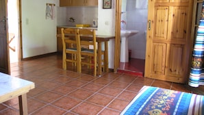 Une cuisine avec des meubles en bois, un évier et un coin repas avec des chaises.
