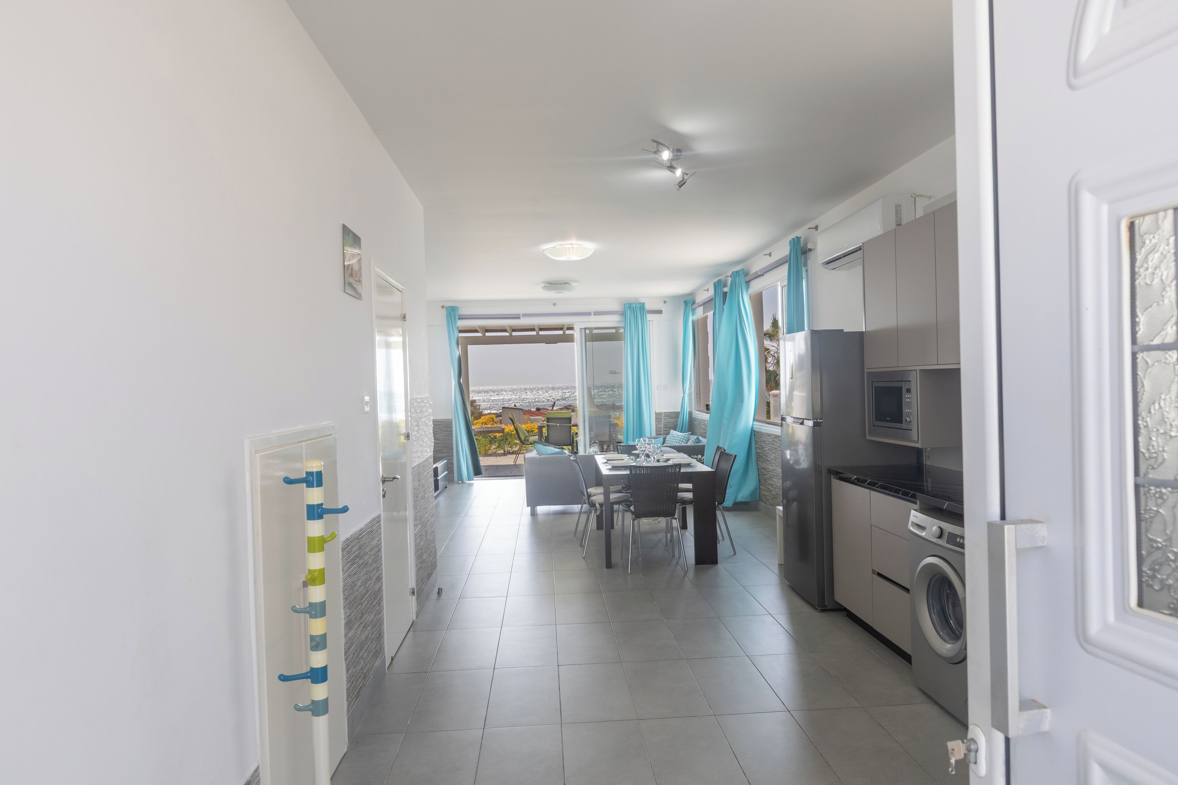 Een moderne keuken met een eethoek, een wasmachine en uitzicht door de glazen deur.