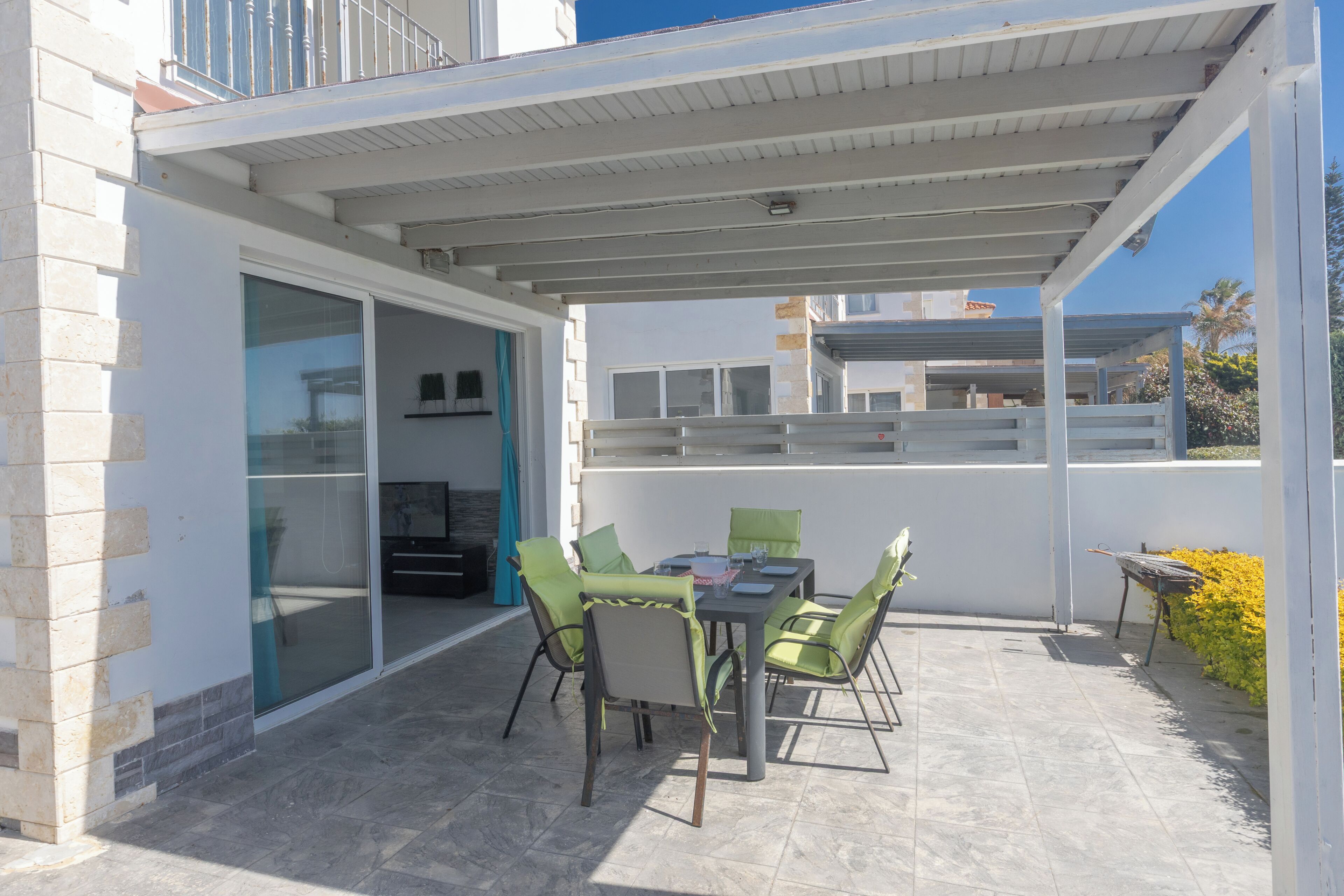 Un patio al aire libre con mesa y sillas, una zona cubierta y vistas de los edificios circundantes.
