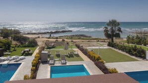 A pool area with lounge chairs and a view of the ocean. - Villa Suri, Luxury Seafront Villa (Sotira)