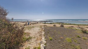 A coastal landscape with a rocky path, a clear sky, and the ocean in the background. - Villa Suri, Luxury Seafront Villa (Sotira)