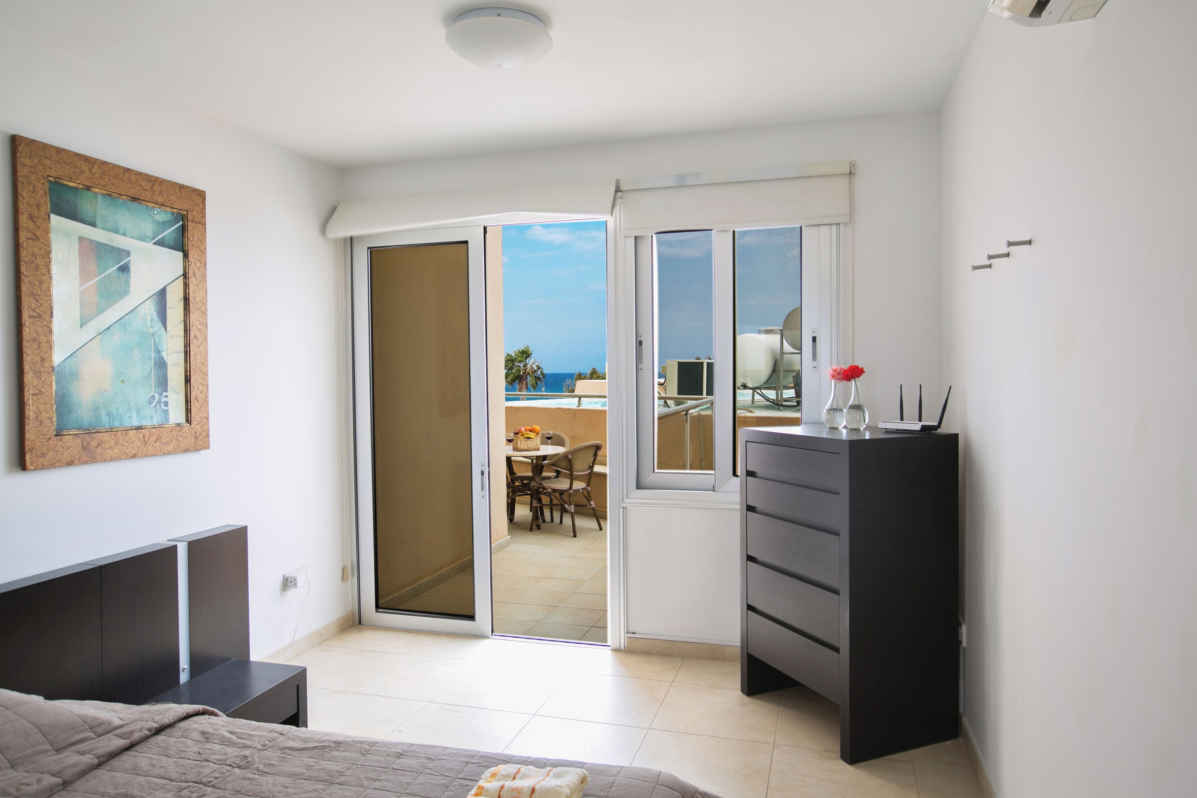 A bedroom with a bed, a dresser, and a painting on the wall.