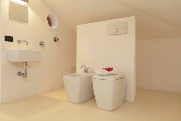Un baño pequeño y moderno con lavabo, bidé e inodoro.