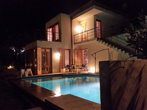 Una casa de dos pisos con piscina, una escalera y un balcón.