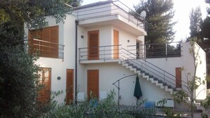 A two-story building with a balcony, a staircase, and a pool area.