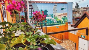 Una escalera con un mural que muestra un puente y una iglesia, rodeada de plantas en macetas.