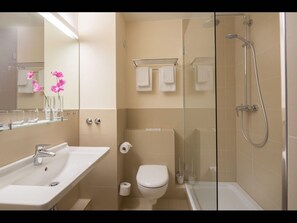 Features a sleek vanity, glass shower enclosure, and separate toilet area.