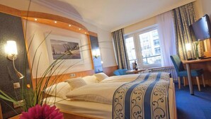 Une chambre d’hôtel équipée d’un lit, d’un bureau, d’une chaise, d’une télévision et d’une fenêtre avec des rideaux.