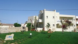 A modern hotel with a flat roof, a staircase, and a signboard in the foreground. - Spacious Family Apartment With Sea View And Swimming Pool (Rethymno)