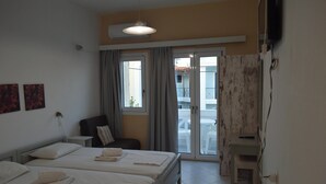 A hotel room with two beds, a chair, a desk, an air conditioning unit, and a view of the outside balcony. - Renia Studios Standard Studio Overlooking the Swimming Pool 8 (Malevizi)