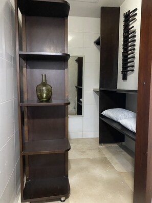 Ein kleines Zimmer mit einer niedrigen Holzregaleinheit, einer kleinen Vase, einem Spiegel und einem Etagenbett.